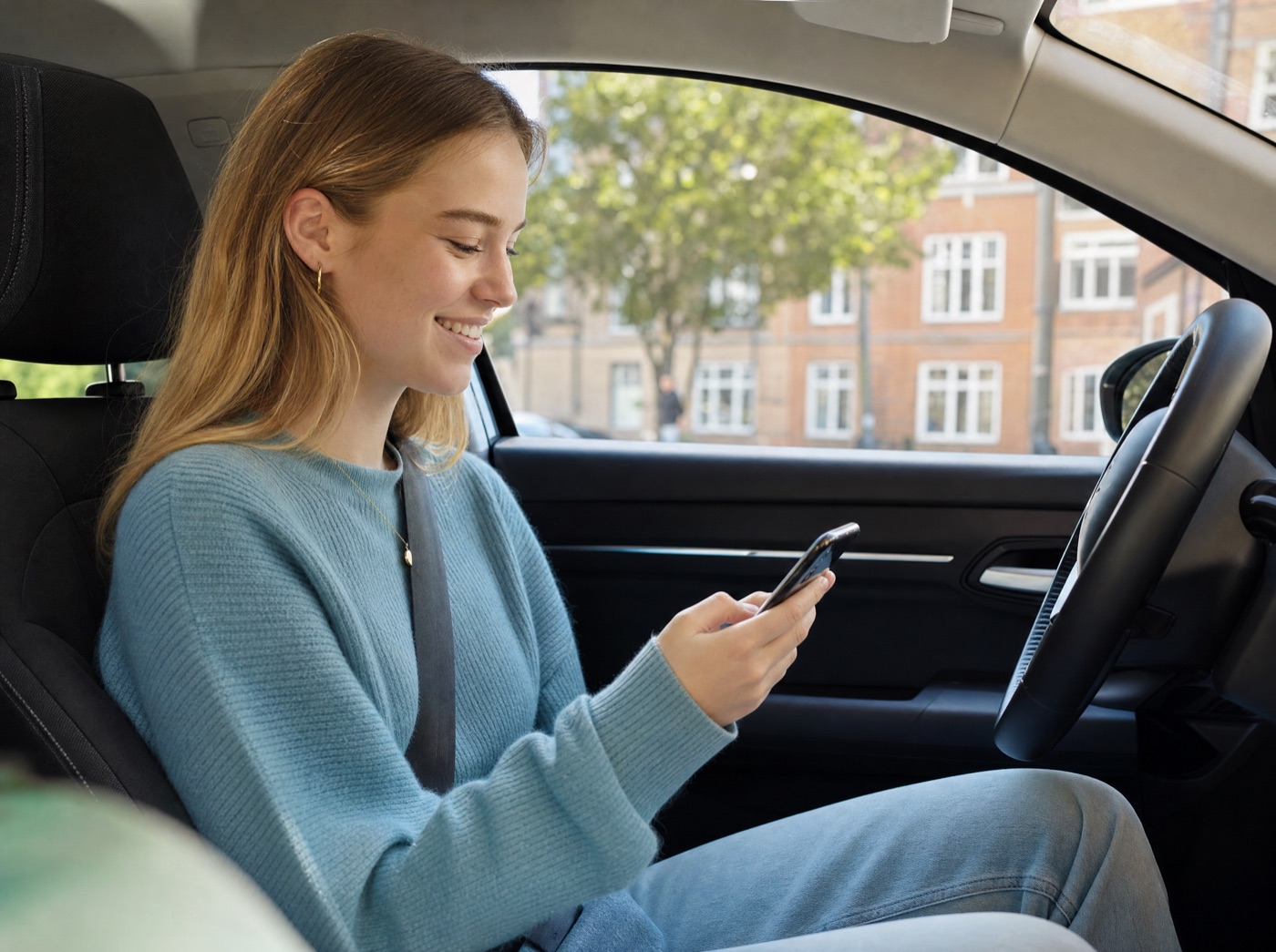 Elev sidder i en bil og ser sit forløb i Alliance-appen på mobilen.
